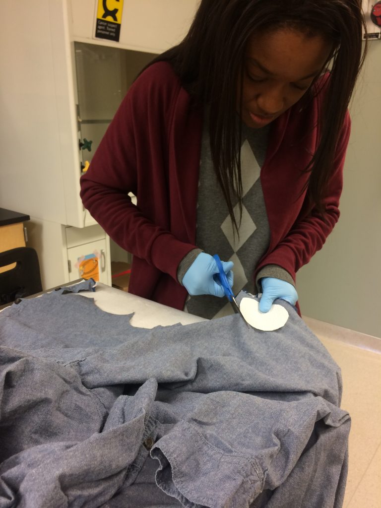 Nwanne Agada, MS Environmental Health student, cutting swatches from a permethrin-treated clothing for further testing